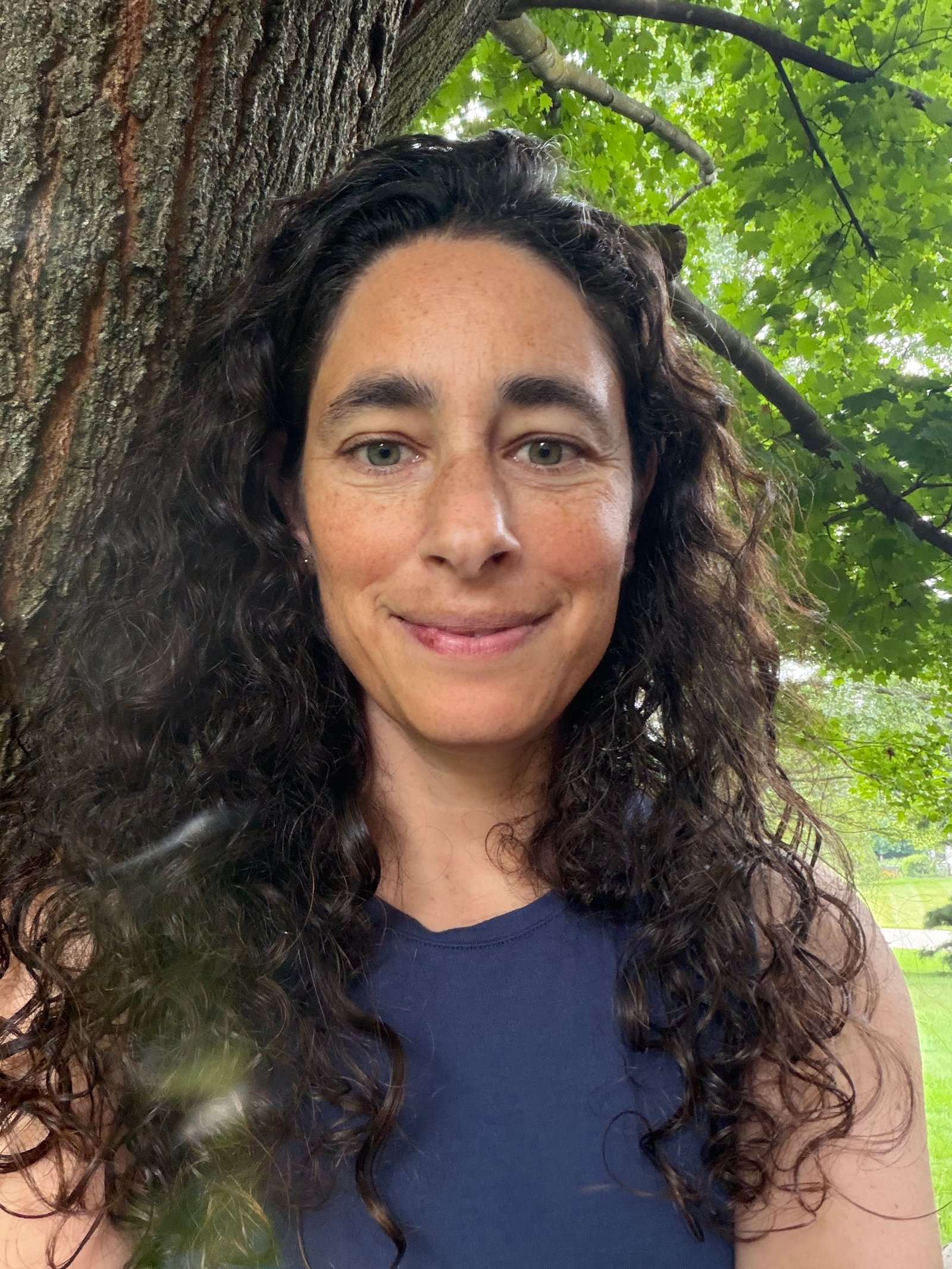 Afifa Corrigan outdoors beside a tree